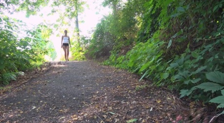 Short taken girl Ali Bordeaux takes a pee while walking on a path in the woods