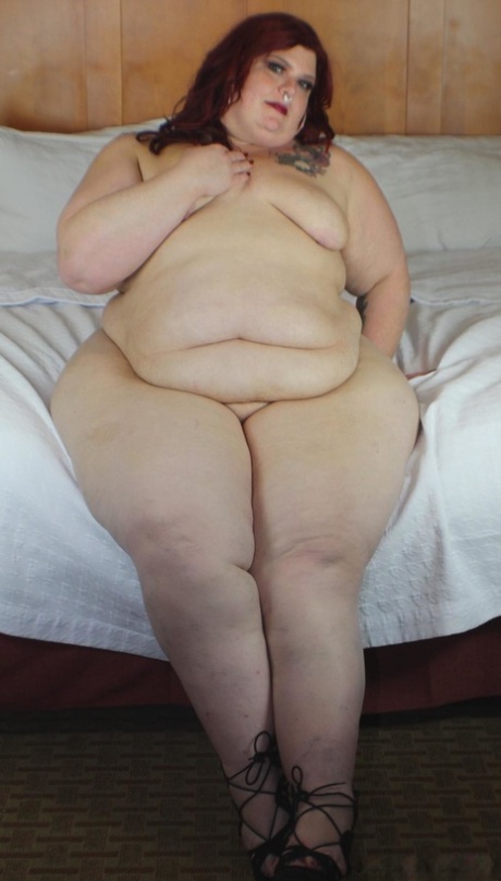 Redhead SSBBW Nikki Cakes shows her massive ass while face down on a bed
