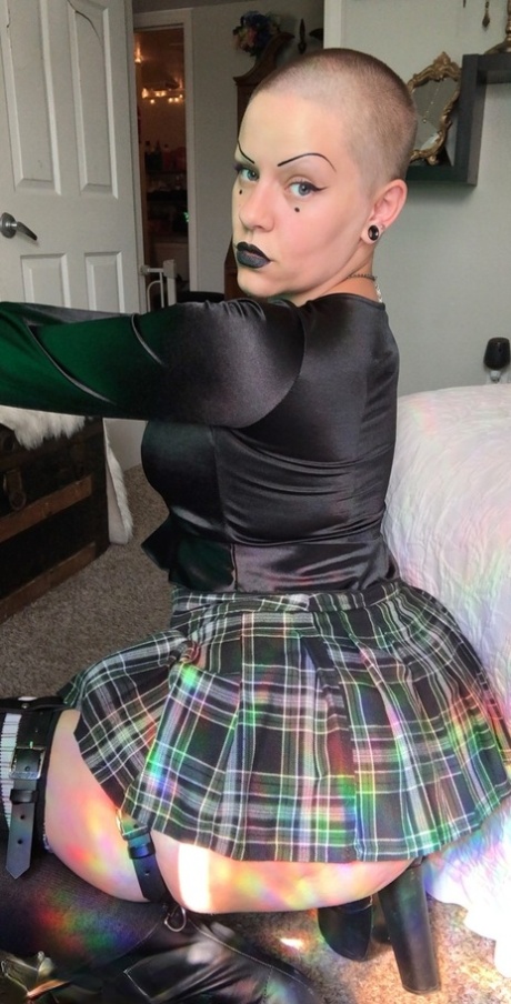 Bald MILF Miss Goth Booty shows her big ass and poses in a plaid skirt